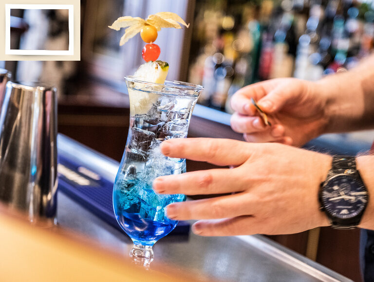 Der Barkeeper serviert einen frischen Cocktail mit ansprechender Dekoration in einem eleganten Glas.