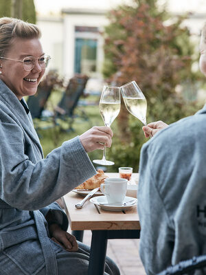 Zwei Frauen genießen Wein auf der Poolterrasse des 4-Sterne-Hotels Holzapfel in Bad Füssing.