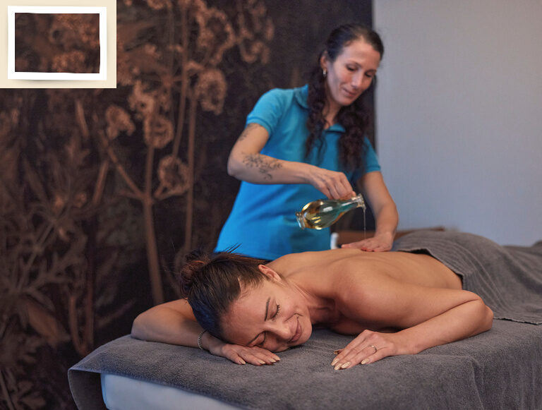 Eine Frau genießt eine entspannende Körperbehandlung von einer Masseurin in der Spa-Welt des Wellnesshotel Holzapfel.