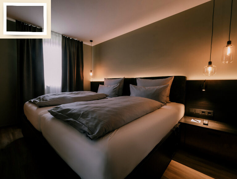 Helles Lampenlicht fällt auf das Doppelbett der Suite Jonagold im Gesundheitshotel Holzapfel bei Passau nahe einem Fernseher.