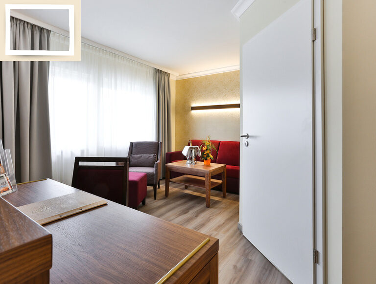Das Doppelzimmer Comfort im Thermenhotel Holzapfel in Bayern bietet beim Eingang einen Schreibtisch mit Stuhl und einen gemütlichen Sitzbereich.