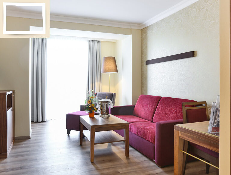 Eine gemütliche Couch im Doppelzimmer Premium des Wellnesshotels Holzapfel Bad Füssing mit Blick auf den Flachbildfernseher.