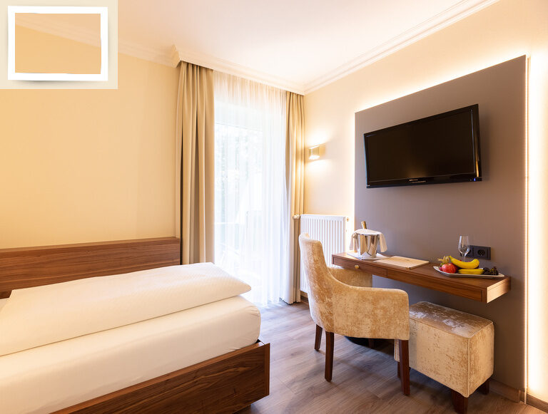 Schlafzimmer im Einzelzimmer Standart des Wellnesshotels Holzapfel mit einem komfortablen Bett, Schreibtisch und Fernseher.