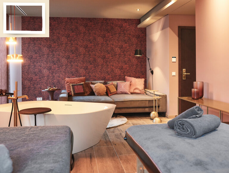 Gemütliches Wellnesszimmer im Wellnesshotel Holzapfel mit kuscheliger Couch, Massageliegen und einer großen Badewanne zum Entspannen.