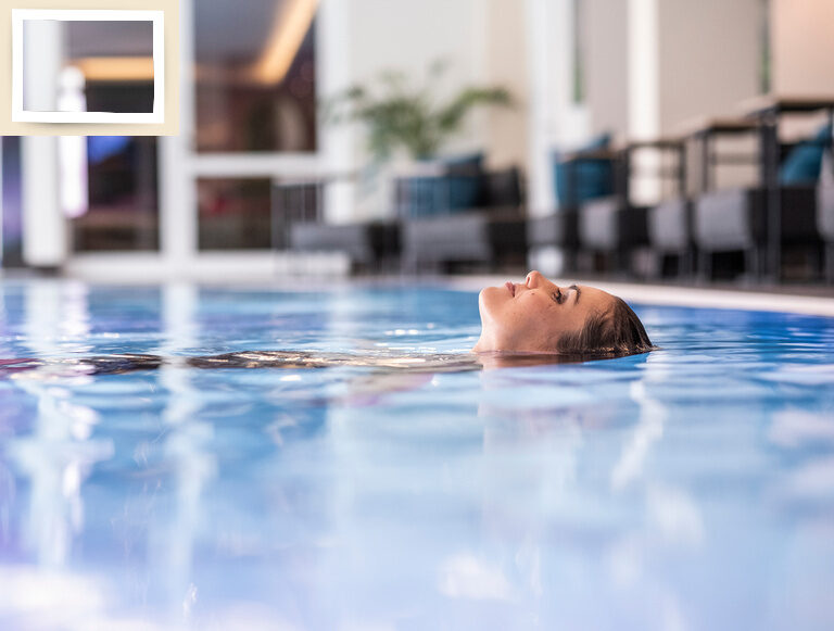 Eine Frau schwebt entspannt im Hotelpool des Wellnesshotel Holzapfel in Niederbayern