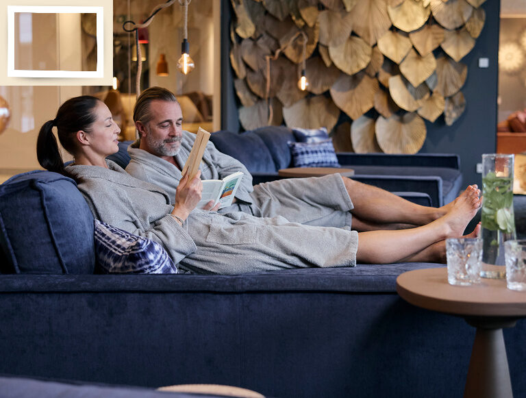 ein Paar genießt die Ruhe beim Lesen im einladenden Ruhebereich des Thermenhotels Holzapfel.