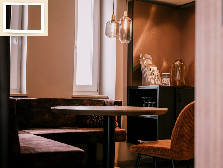 Eine sorgfältig gestaltete Suite Goldrenette mit Tisch, Stühlen und Lichtelementen zum Erholen im Thermenhotel Holzapfel in Bayern.