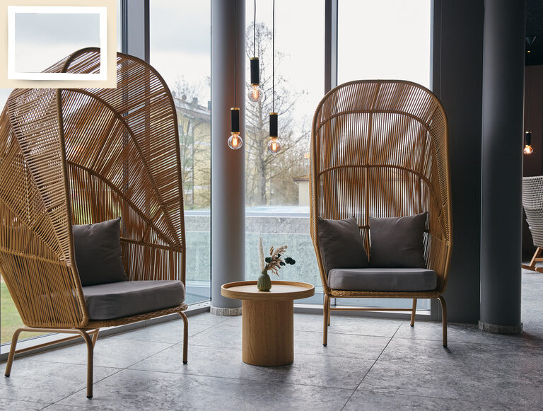 Zwei moderne Stühle in einem Raum mit großen Fenstern.