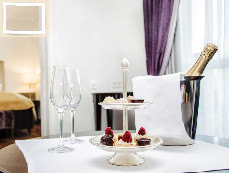 Weingläser und ein kleines Buffet mit Desserts als zentrale Elemente auf einem festlichen Tisch in der Suite Gala des Gesundheitshotels Holzapfel in Niederbayern.