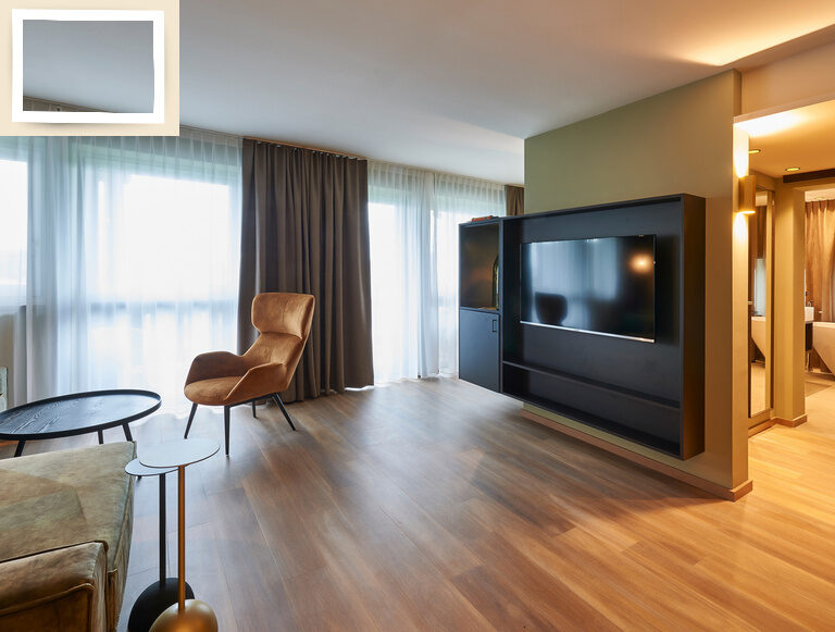 Ein geschmackvoll eingerichtetes Wohnzimmer in der Suite Jonagold mit Holzböden und einem Flachbildfernseher.