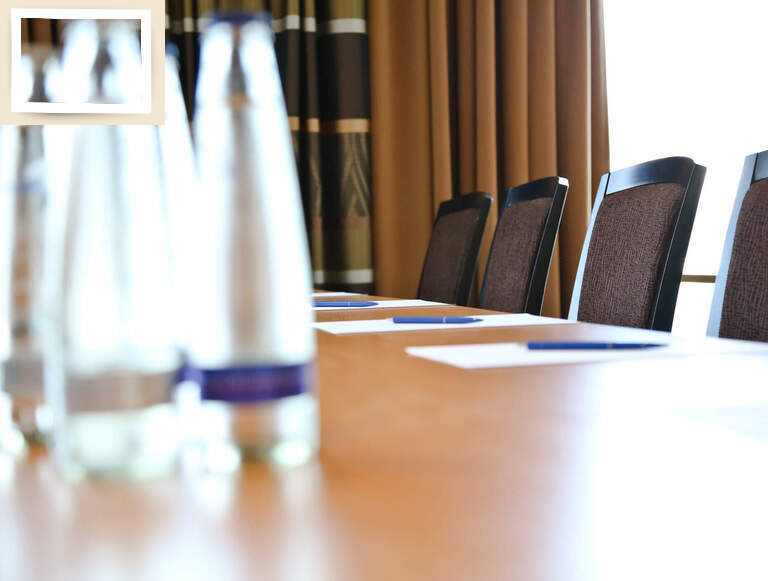 Ein Tagungstisch mit frischem Wasser und bereitgestellten Blöcken und Stiften im Seminarhotel Holzapfel bei Passau..