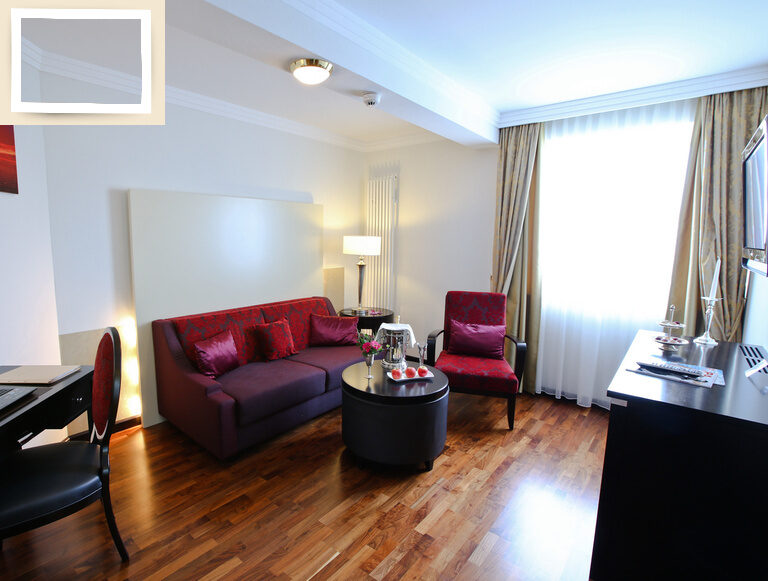 Luxuriöser Wohnbereich in der Suite Elstar, der ein einladendes Sofa und einen Schreibtisch zum Arbeiten im Thermenhotel Holzapfel in Bayern bietet.