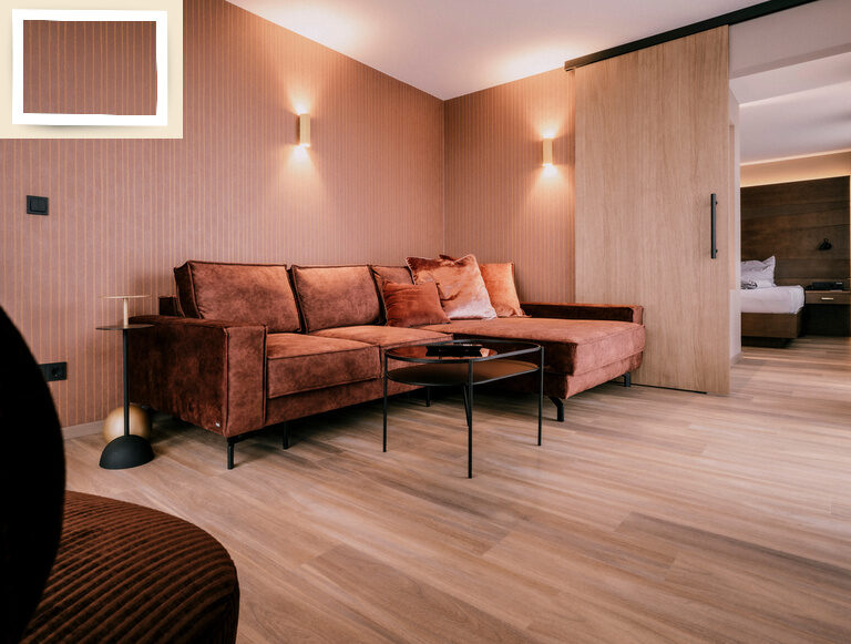 Ein braunes Sofa steht im Mittelpunkt des Wohnbereichs der Suite Goldrenette, umgeben von warmer Holzoptik des Wellnesshotels Holzapfel in Niederbayern.