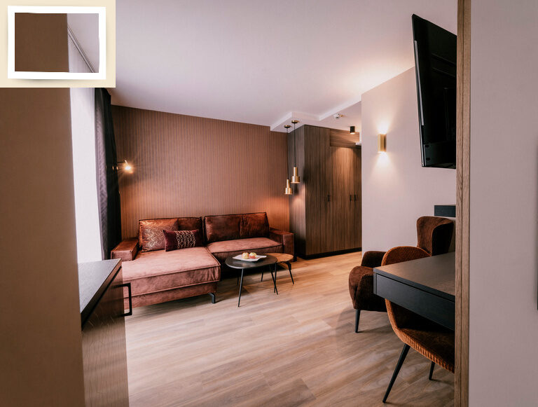 Einladender Wohnbereich in der Suite Goldrenette im Wellnesshotel Holzapfel in Bad Füssing mit Sicht auf einen Fernseher.