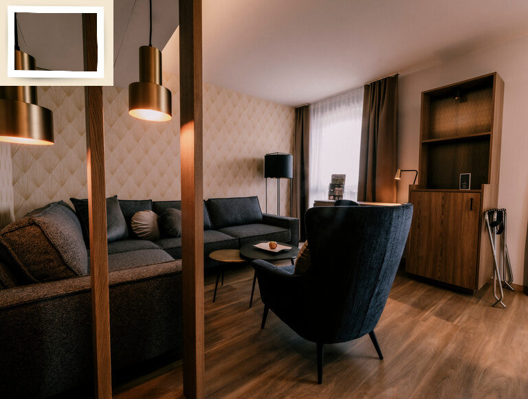 Gemütlicher Wohnbereich mit stilvoller Couch und einem Sessel im Doppelzimmer Premium des Hotel Holzapfel im Rottal.