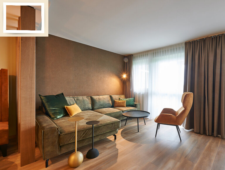Gemütliche Sitzecke mit eleganter Beleuchtung und einem großen Fenster in der Suite Jonagold des Thermenhotels Holzapfel bei Passau.