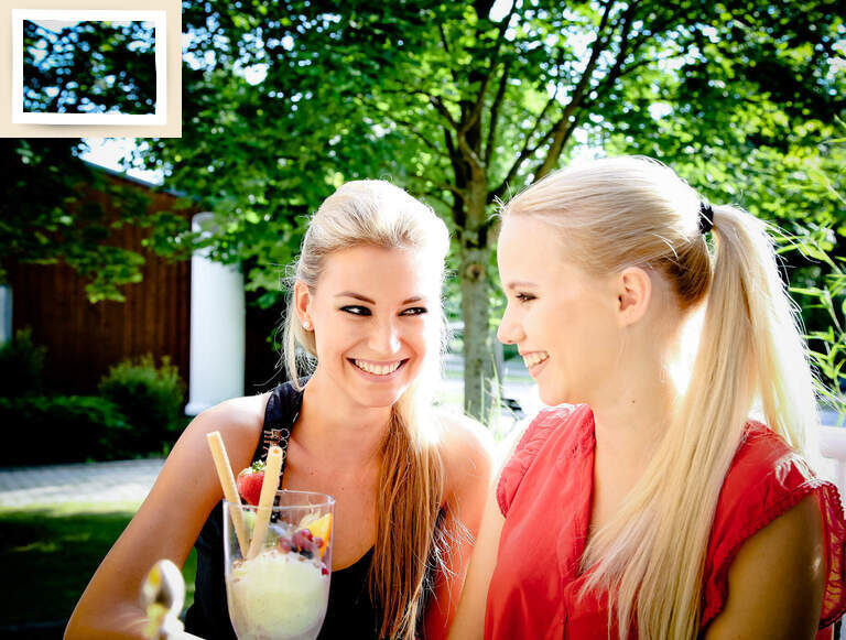 Zwei Frauen sitzen auf der sonnigen Terrasse des Gesundheitshotels Holzapfel in Bad Füssing und genießen Cocktails.