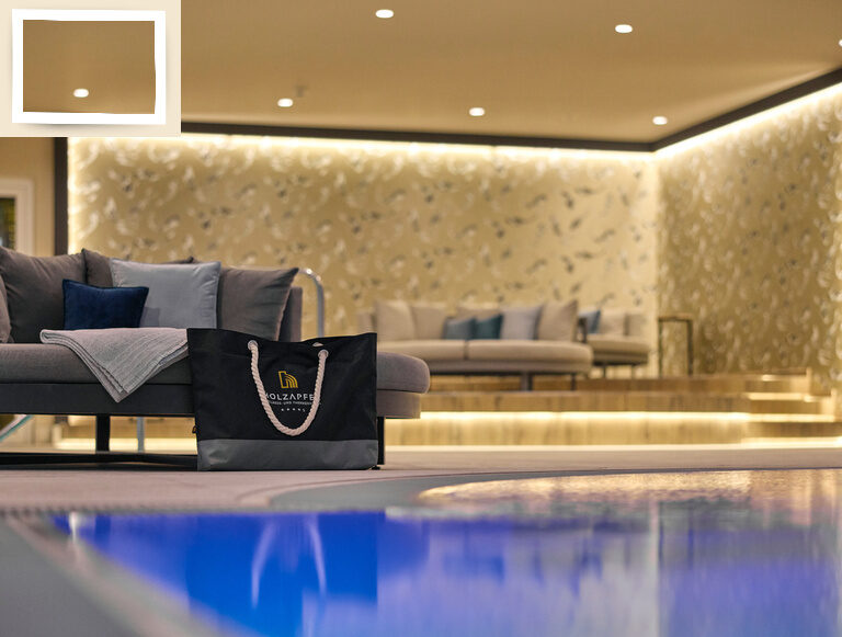 Eine gemütlich luxuriös gestaltete Sitzgelegenheit neben dem Innenpol vom Thermenhotel Holzapfel in Bayern.