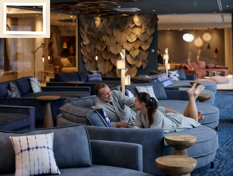 Ein Paar entspannt im komfortablen Ruheraum mit großen runden Liegecouchen im Spa des Thermenhotels Holzapfel in Bayern.